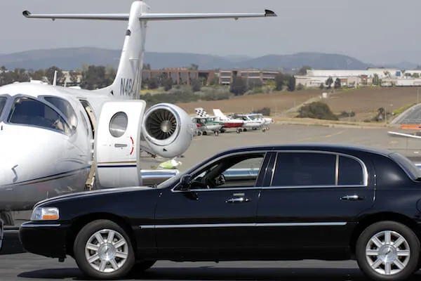 airport-transfers-hamden-ct-1920w A private jet parked on a tarmac beside a black luxury car.