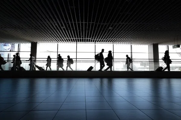 airport-transportation-to-LGA-1920w Silhouetted travelers with luggage walk through an airport terminal.